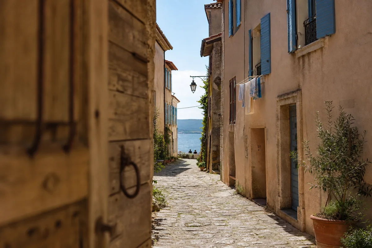 Ruelle provençale animée avec façades colorées et portes anciennes en bord d’étang