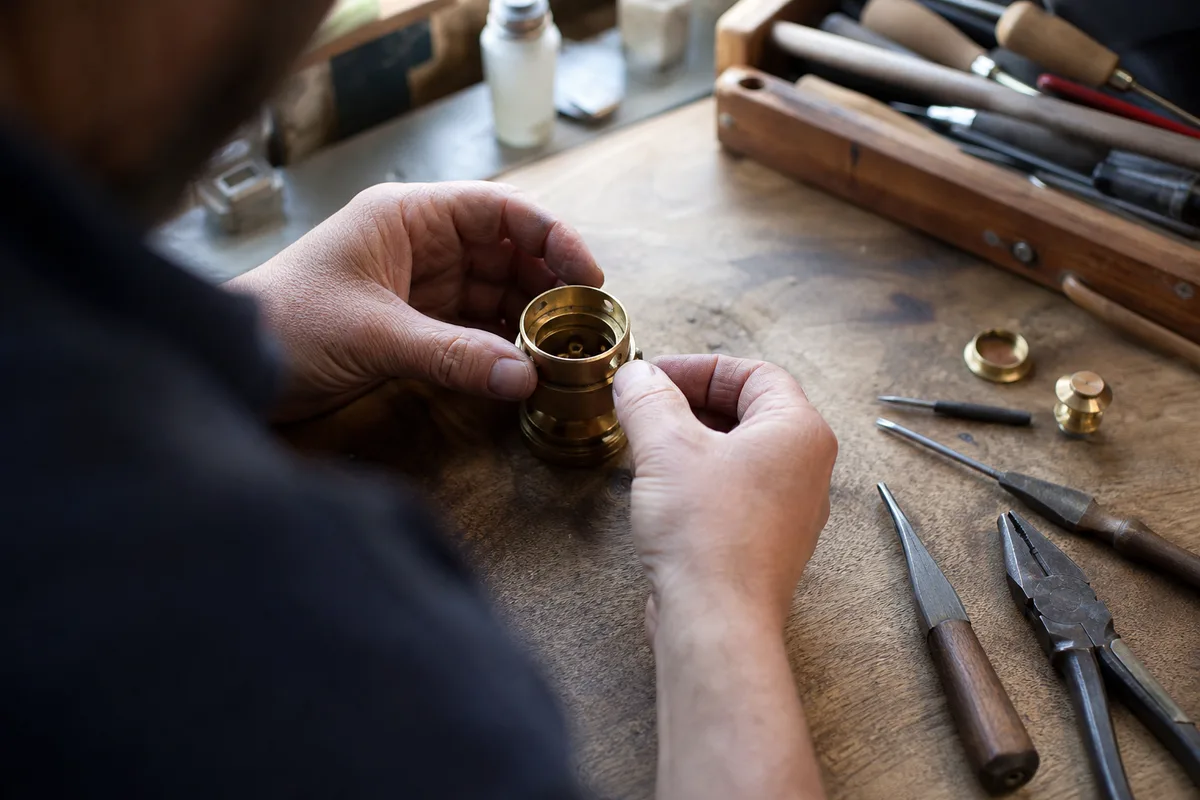 Serrurier examinant un cylindre de porte démonté sur une table d&rsquo;atelier, gros plan sur les mains